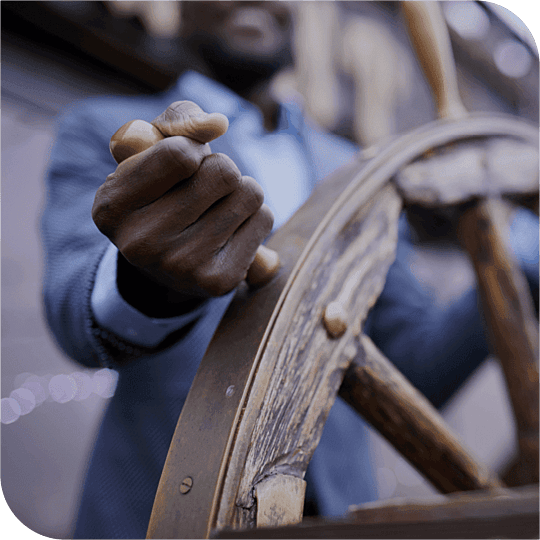 A captain steering his ship with hands on the wheel.